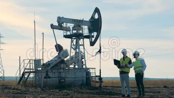 石油生产现场与两名工程师讨论旁边的东西石油工业石油工业石油部门视频的预览图