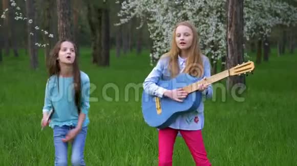 在森林公园里模仿流行音乐人表演快乐的小女朋友围着跳舞唱歌弹吉他视频的预览图