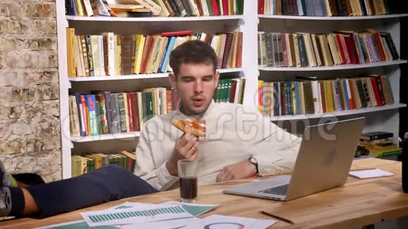 带着书的舒适房间里的时间流逝高加索人一边吃着比萨饼一边看着一边喝着可乐视频的预览图