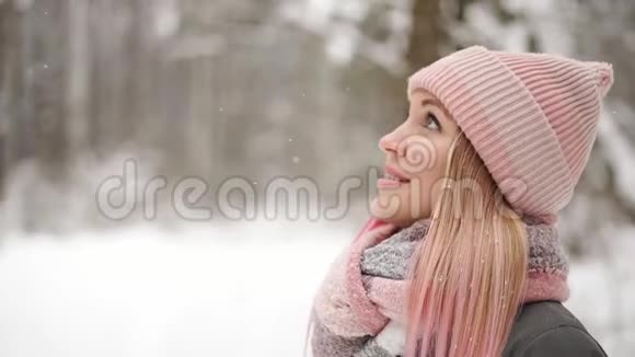 穿着夹克和帽子的女人慢慢地看着雪看到雪花微笑视频的预览图