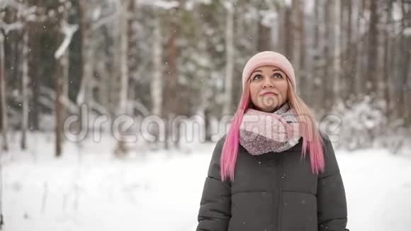 穿着夹克和帽子的女人慢慢地看着雪看到雪花微笑视频的预览图