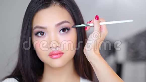 专业化妆师用刷子为漂亮的亚洲女人完成时尚的自然化妆视频的预览图
