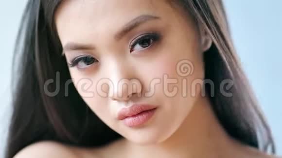 迷人的亚洲时尚模特的特写肖像淡褐色的眼睛和长长的睫毛慢动作视频的预览图