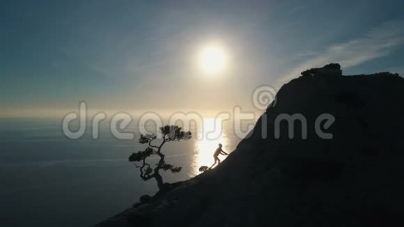 空中剪影年轻女子爬上一座山女士在美丽的风景中到达山顶视频的预览图