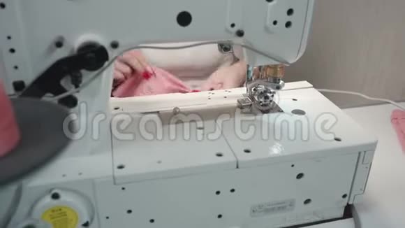 裁缝女人在电动机器上缝制粉红色衣服的视频视频的预览图