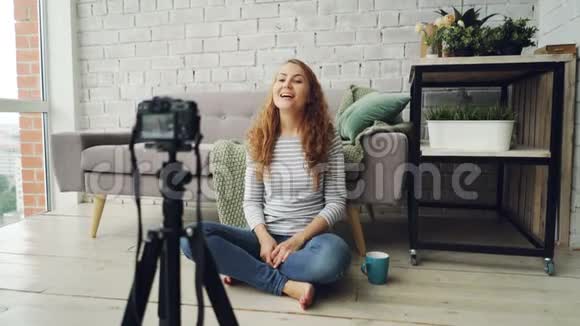 快乐的女性博客作者正在录制视频用于网络视频聊天和手势显示拇指和挥动的手视频的预览图