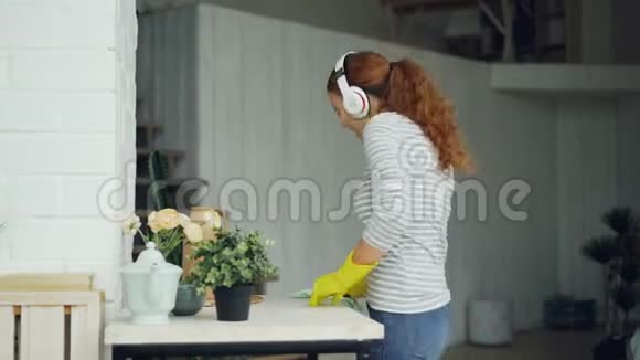 迷人的年轻女性有趣的管家在打扫房间的时候玩得很开心年轻的女士在唱歌跳舞听着视频的预览图