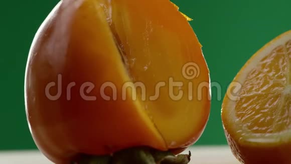 首先我们看到一个柿子然后视频从左到右移动我们看到一个橘子切成碎片绿色的背景视频的预览图