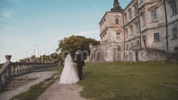 新婚夫妇手牵手走在城堡里互相亲吻视频的预览图