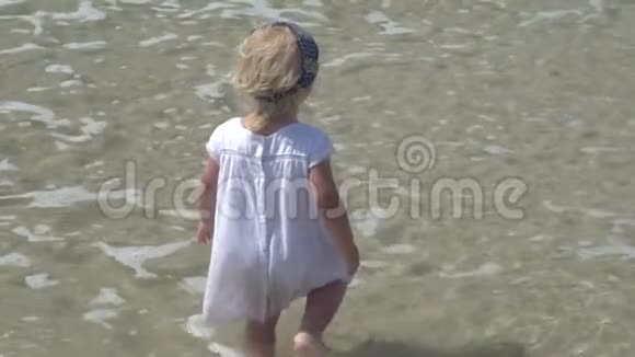 一个孩子站在海水里穿着白色连衣裙的小女孩在海水中散步愤怒的孩子视频的预览图
