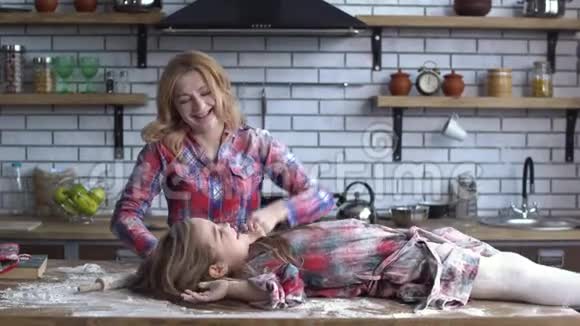 无忧无虑美丽的年轻母女在厨房里糊弄面粉妈妈和孩子玩得开心视频的预览图