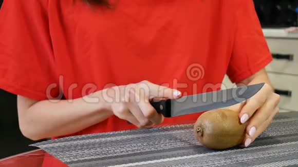 在厨房里用刀子把雌性的手收起来切鲜猕猴桃健康的生活方式和饮食观念视频的预览图