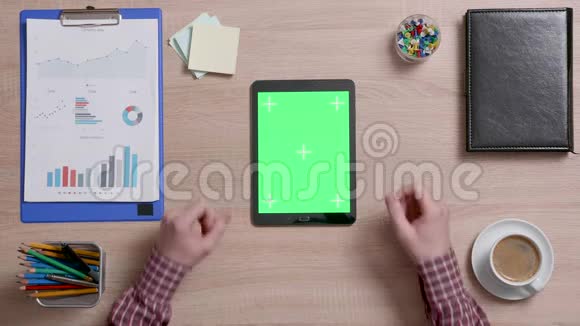 男性手在黑色平板电脑上的绿色屏幕底部边缘滚动的俯视图视频的预览图