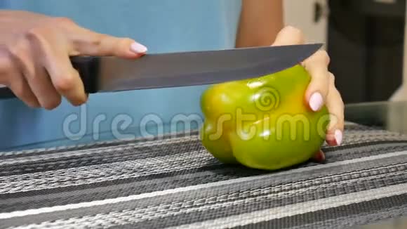 女性手在厨房里用刀切新鲜的青椒视频的预览图