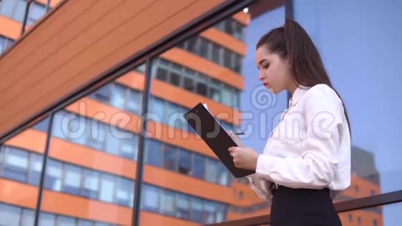 黑发的商务女孩正在商务中心附近的工作文件中做笔记4K视频的预览图