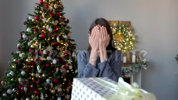 美丽的女人享受圣诞礼物和欢乐的跳跃在圣诞树的背景上装饰的家新年快乐视频的预览图