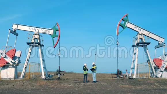 石油开采现场与两名工程师沟通能源石油天然气燃油抽油机视频的预览图