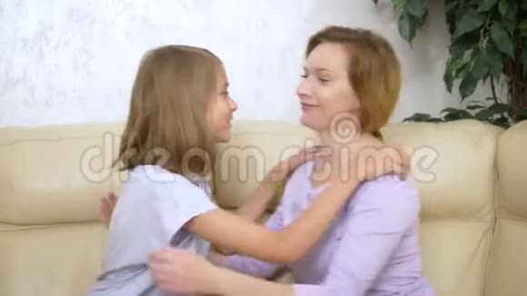 家庭信任的概念幸福的女儿悄悄地向坐在客厅沙发上的母亲一个秘密视频的预览图