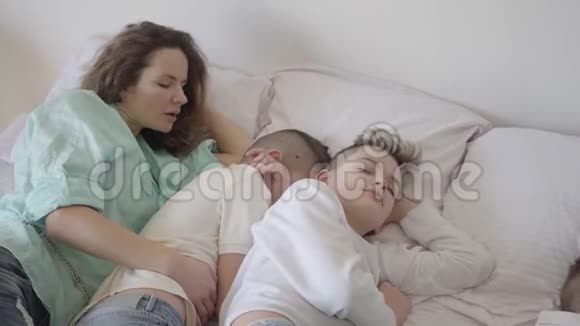 描绘年轻的母亲和她的十几个儿子睡在大床上一个男孩坐在椅子上快乐的爱视频的预览图