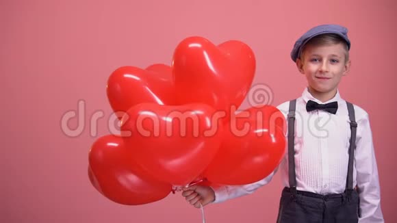 穿着老式衣服的小男孩带着心形气球微笑情人节视频的预览图