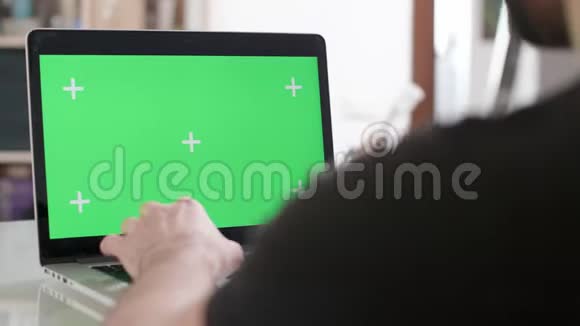 一名男子用绿色屏幕在他的笔记本电脑上工作时滑鼠的肩膀被击中视频的预览图