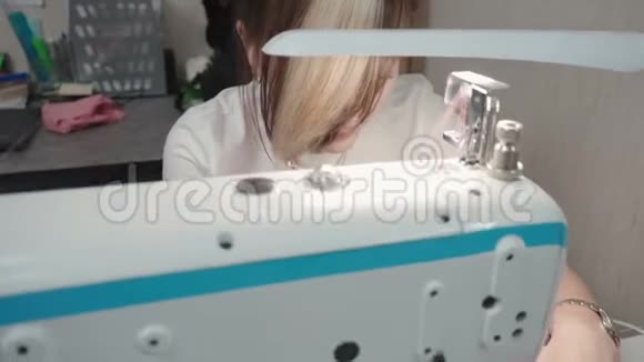 裁缝女士在电动机器上缝制粉红色连衣裙的视频视频的预览图