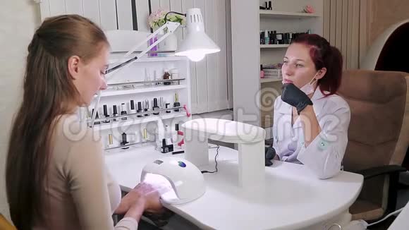 一家美容院的女顾客用紫外线灯擦指甲视频的预览图