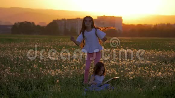快乐的姐妹们在户外玩吉他跳舞在户外跳跃日落时分黄昏时分蒲公英的田野视频的预览图