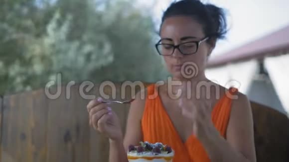 特写戴眼镜的美女借助勺子从杯子里拿出一片甜点吃了下去视频的预览图