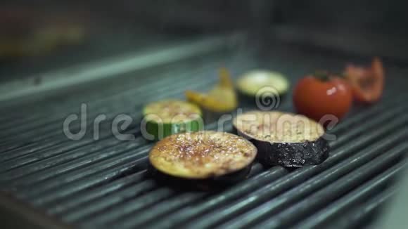 厨师手特写用金属钳子将蔬菜西红柿茄子黄椒放在烤架上厨师视频的预览图