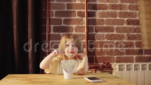 一个可爱的小女孩在砖墙附近的一个白色大罐子里吃酸奶视频的预览图
