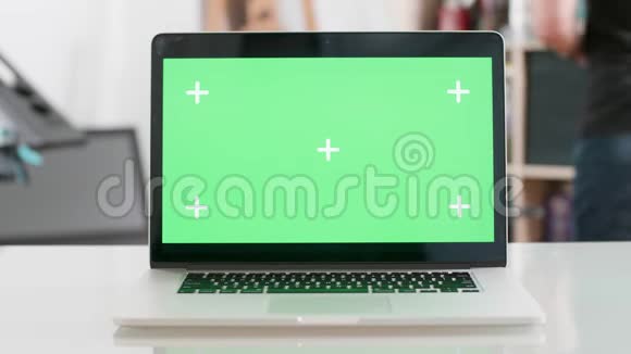 笔记本电脑上的绿色屏幕显示在模糊的背景上视频的预览图