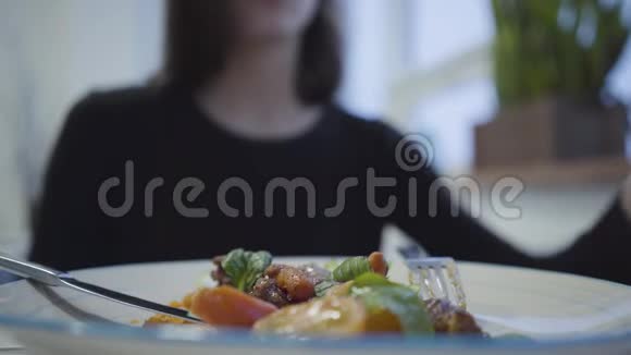 坐在舒适的餐厅里一个年轻漂亮的女孩用红色的指甲盐做了一道美味可口的菜肴闭合视频的预览图