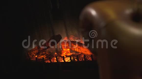在模糊的棕色皮革沙发背景下带有人造闪光火焰和燃烧红色煤的电动壁炉视频的预览图