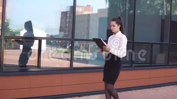 黑发的年轻商务女孩手里拿着文件来到商务中心附近慢动作视频的预览图