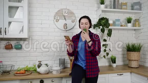可爱的女孩在电话里读短信在厨房里吃巧克力视频的预览图