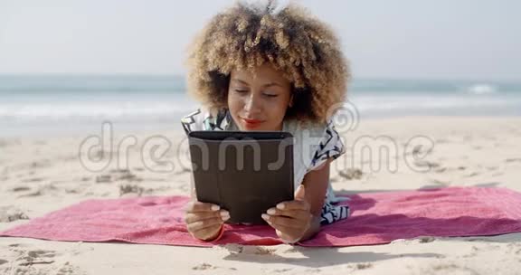 女人在海滩上使用平板电脑视频的预览图