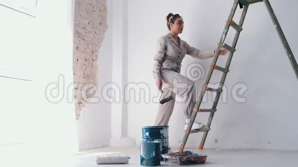 女孩爬上梯子手里拿着油漆滚筒视频的预览图