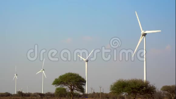 风力涡轮机生产环保的绿色清洁的电力底部有树木蓝天和云层视频的预览图