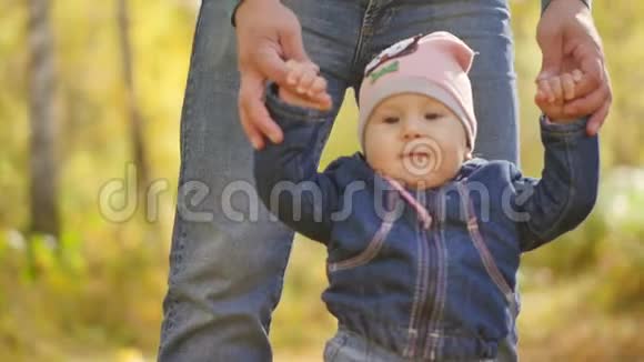 父亲牵着一个小孩子的手在秋天的公园里慢动作视频的预览图
