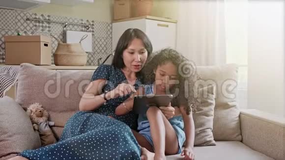 母亲和女儿在家庭内部的数字平板电脑上玩得很开心一对可爱快乐的母女用数字视频的预览图