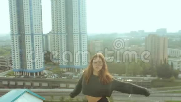 一个年轻迷人的女人正在日出的背景下与城市景观一起跳舞和伸展自由视频的预览图