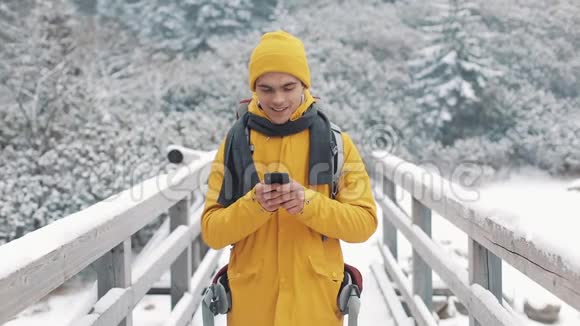 一位年轻的游客站在桥上使用智能手机他制作了sephi并在社交网络上发布了照片冬季视频的预览图