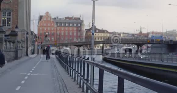 两个骑自行车的人骑在运河旁边的自行车道上视频的预览图
