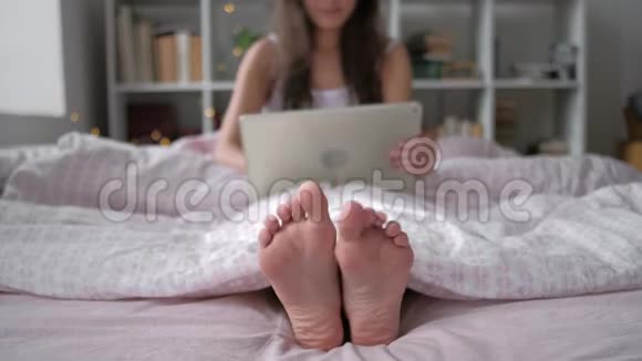 科技互联网和人的概念幸福的年轻女子躺在床上平板电脑在家里的卧室里视频的预览图