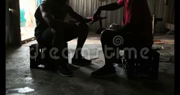 美国黑人男教练协助拳击手在4k健身房穿手包视频的预览图