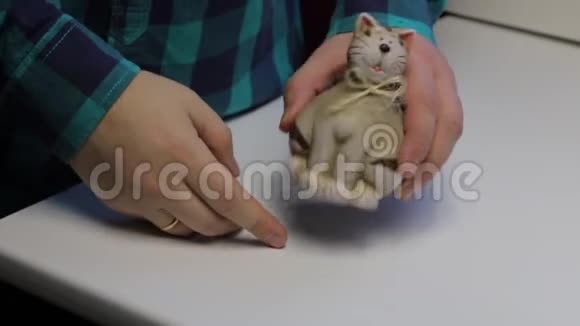 桌子上是一只猫形的储蓄罐一个人拿着一个储蓄罐打开它他从储蓄罐里倒出硬币视频的预览图