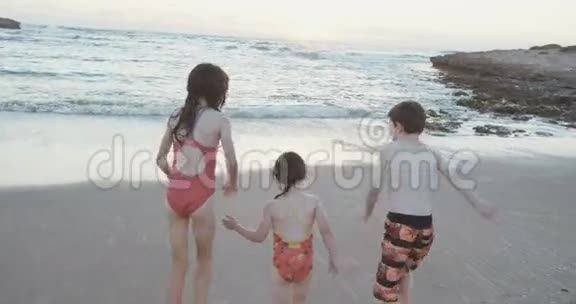 日落时三个孩子在海滩上玩耍的照片视频的预览图