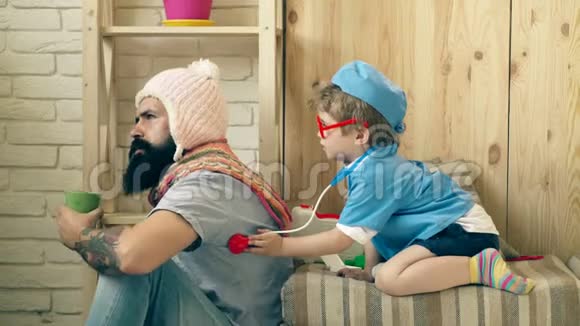 一个留胡子的人在一个小医生的接待处一个穿着医生西装小男孩对待一个留胡子的人a的概念视频的预览图
