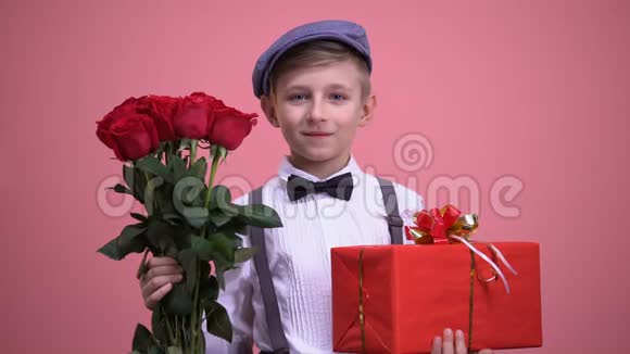 男孩穿着可爱的老式衣服带玫瑰花束和礼品盒情人节视频的预览图